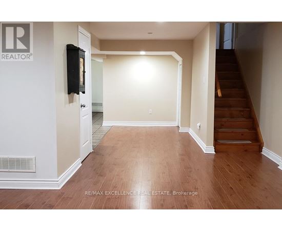 A hallway with wooden floors and a staircase on the right.