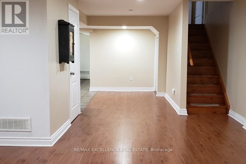 A hallway with wooden floors and a staircase on the right.