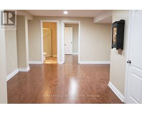 A spacious room with wooden flooring and white walls.
