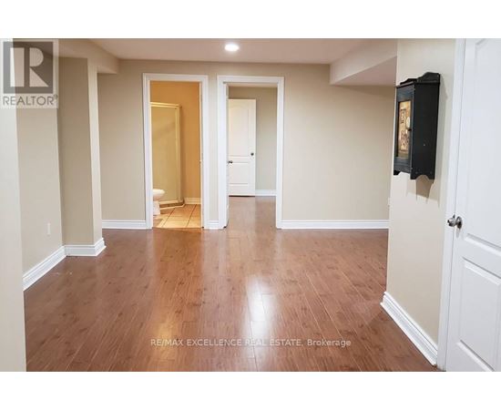 A spacious room with wooden flooring and white walls.