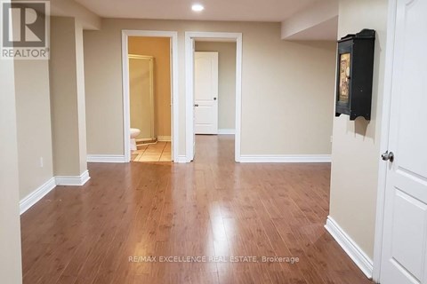 A spacious room with wooden flooring and white walls.