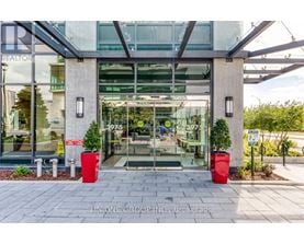 The front of a building with a glass door and two red planters on either side.