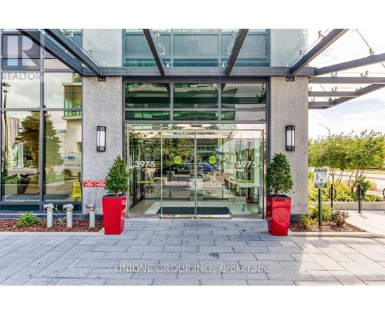 The front of a building with a glass door and two red planters on either side.