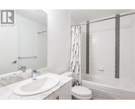 A white bathroom with a marble sink and a toilet.