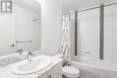 A white bathroom with a marble sink and a toilet.