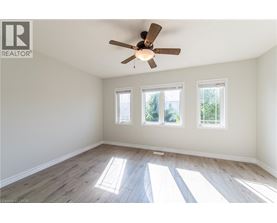 A room with a ceiling fan and three windows.