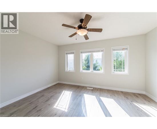A room with a ceiling fan and three windows.