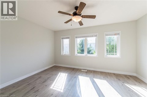 A room with a ceiling fan and three windows.
