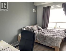 A bedroom with a bed, chair, and window.