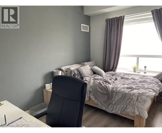 A bedroom with a bed, chair, and window.