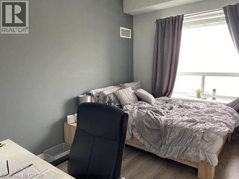 A bedroom with a bed, chair, and window.