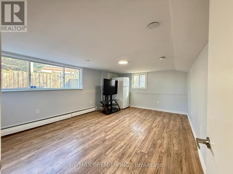 A spacious room with wooden flooring and a flat-screen TV.