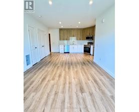 A spacious room with wooden flooring and white walls.