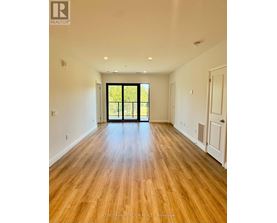 A room with wooden floors and a sliding glass door leading to a green outdoor area.