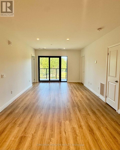 A room with wooden floors and a sliding glass door leading to a green outdoor area.