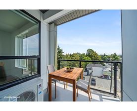 A balcony with a table and chairs overlooking a parking lot.