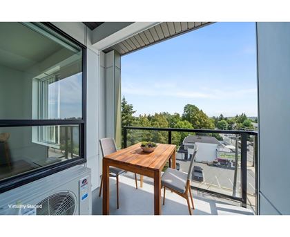 A balcony with a table and chairs overlooking a parking lot.