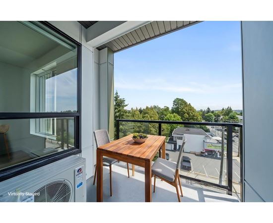A balcony with a table and chairs overlooking a parking lot.
