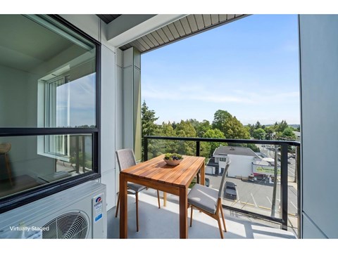 A balcony with a table and chairs overlooking a parking lot.