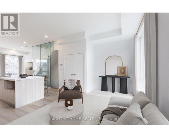 A modern living room with a glass staircase and a grey sofa.