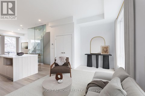 A modern living room with a glass staircase and a grey sofa.