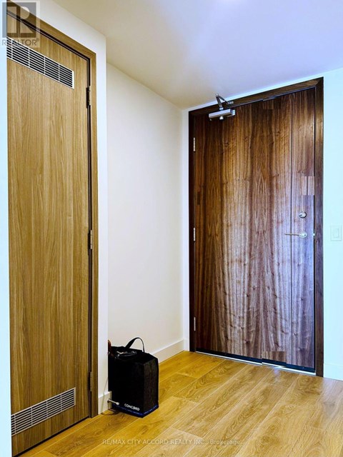 A room with a wooden door and a black box on the floor.