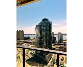 A tall glass building with a view of the water in the background.