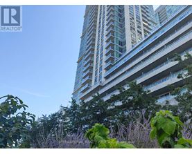 A tall building with balconies is surrounded by greenery.