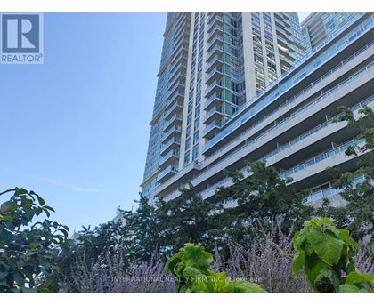 A tall building with balconies is surrounded by greenery.