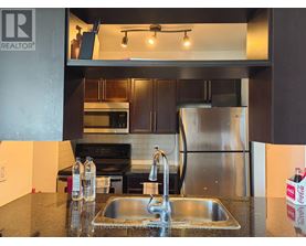 A modern kitchen with a stainless steel refrigerator and a double sink.