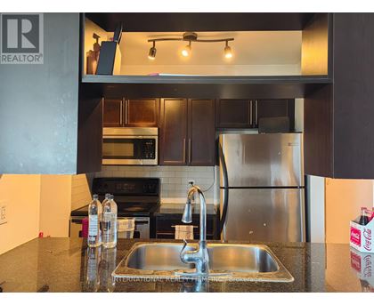 A modern kitchen with a stainless steel refrigerator and a double sink.