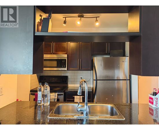 A modern kitchen with a stainless steel refrigerator and a double sink.