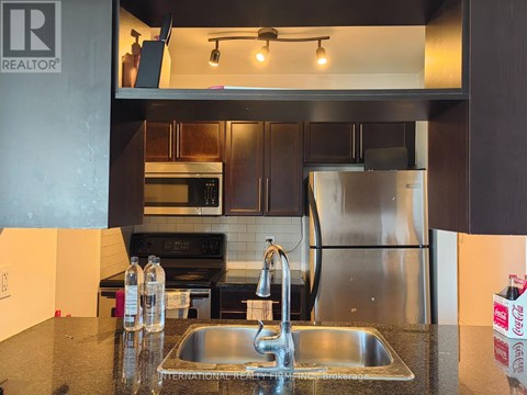 A modern kitchen with a stainless steel refrigerator and a double sink.