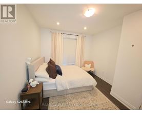A bedroom with a bed, nightstand, and window with curtains.