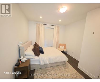 A bedroom with a bed, nightstand, and window with curtains.