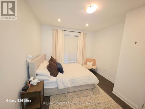 A bedroom with a bed, nightstand, and window with curtains.