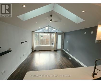 A spacious room with a skylight and a ceiling fan.