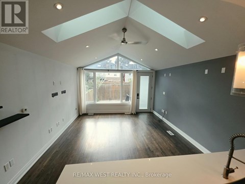 A spacious room with a skylight and a ceiling fan.