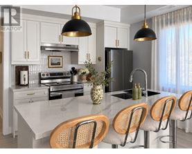 A modern kitchen with a marble countertop and wooden bar stools.