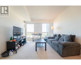 A living room with a grey couch and a black entertainment center.