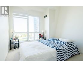 A bedroom with a large bed and a window overlooking a cityscape.