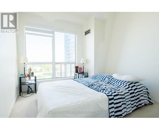 A bedroom with a large bed and a window overlooking a cityscape.