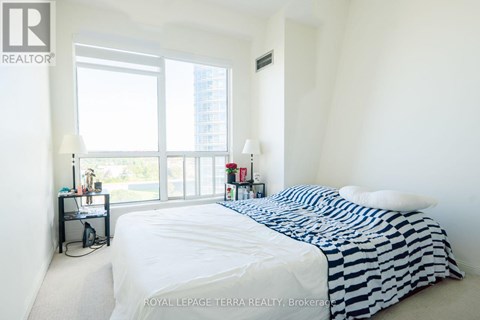 A bedroom with a large bed and a window overlooking a cityscape.