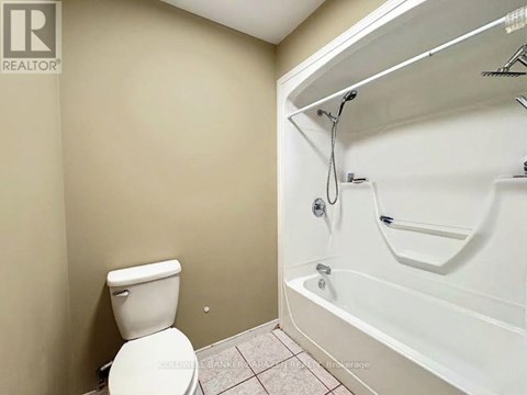 A white toilet sits next to a white bathtub in a bathroom.