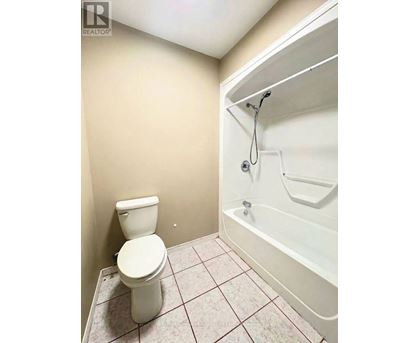 A white toilet sits next to a white bathtub in a small bathroom.