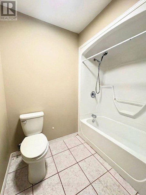 A white toilet sits next to a white bathtub in a small bathroom.