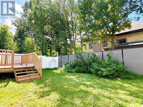 A backyard with a wooden deck and a fence.