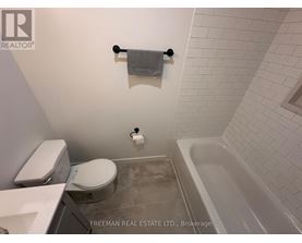 A white toilet and sink in a bathroom with a white tiled wall.