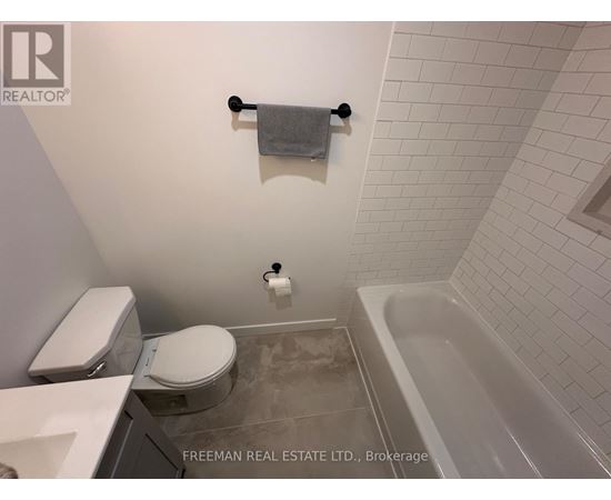 A white toilet and sink in a bathroom with a white tiled wall.
