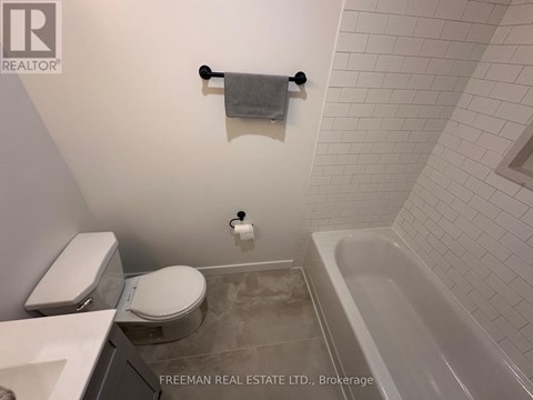 A white toilet and sink in a bathroom with a white tiled wall.